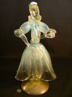 MURANO BLUE & CLEAR MICA GLASS WOMEN FIGURINE: Lot 1106: MURANO BLUE & CLEAR MICA GLASS WOMEN FIGURINE - Women is well dress with a dusting of gold paint around her head, collar,cuffs and on base. No noticeable chips or cracks. Measures 12"