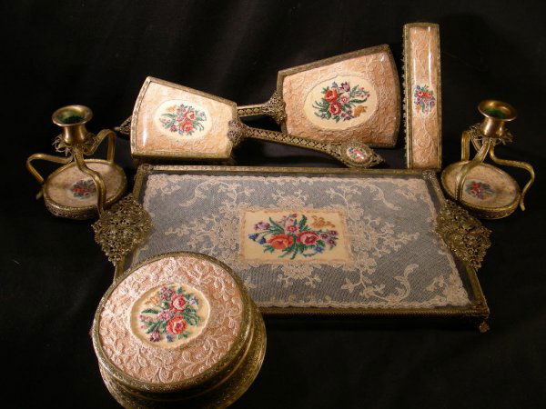 OLD PETIT POINT GILT FILIGREE DRESSER SET 7 PCS: Lot 13: OLD PETIT POINT GILT FILIGREE DRESSER SET 7 PCS - Ornate filigree metal work with antique lace inserts and petit point floral work. Musical jewel box "Blue Danube Waltz" measures 5" wide x 3 1