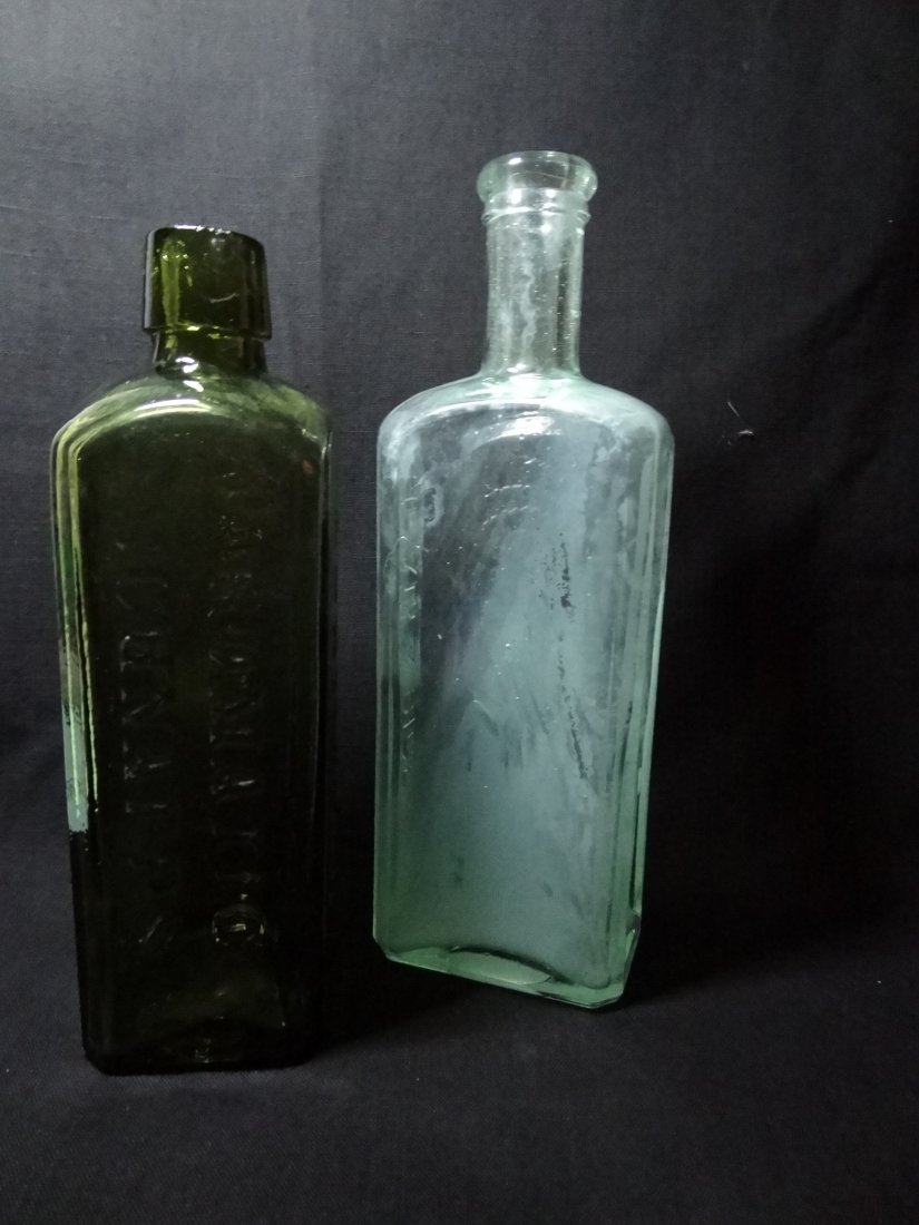 TWO VINTAGE BOTTLES - 1) ''UDOLPHO WOLFE'S / AROMATIC S: TWO VINTAGE BOTTLES - 1) ''UDOLPHO WOLFE'S / AROMATIC SCHNAPPS / SCHIEDAM'' DARK GREEN BOTTLE, 7.5'' TALL X 2 1/4'' SQUARE. 2) 1890 ''HEALY & BIGELOW / INDIAN SACWA'' WITH EMBOSSED INDIAN HEAD ON FRON