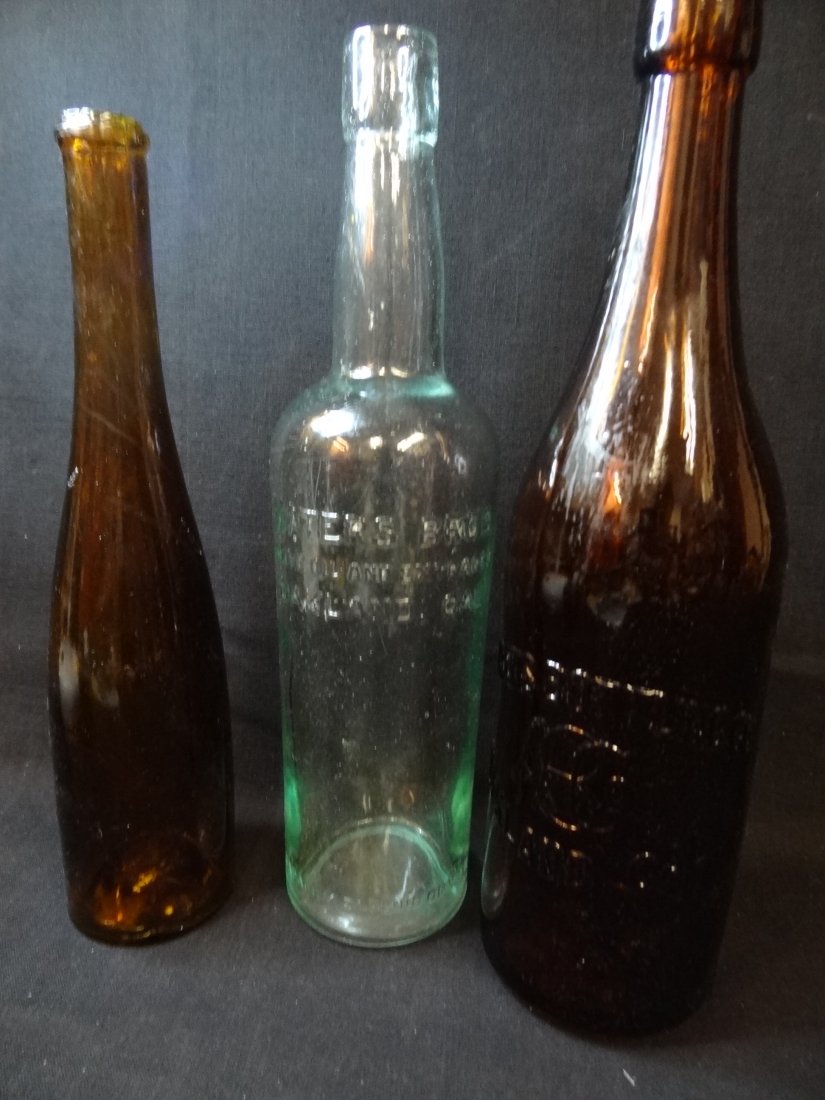 THREE VINTAGE BOTTLES 1) AMBER AHRENS BOTTLING CO OAKLA: THREE VINTAGE BOTTLES 1) AMBER AHRENS BOTTLING CO OAKLAND CAL, 'ABCO' EMBOSSED INSIGNIA, BOTTOM EMBOSSED 'PCCW4' 11.5'' BY 3'' 2) AQUA WATER BROS, 'OLIVE OIL AND EXTRACTS' OAKLAND CAL / CAPACITY 21 FL