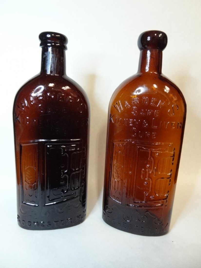 TWO AMBER WARNERS BOTTLES. 'WARNER'S SAFE KIDNEY AND LI: TWO AMBER WARNERS BOTTLES. 'WARNER'S SAFE KIDNEY AND LIVER CURE', ROCHESTER, N.Y. CENTER EMBLEM OF SAFE ON WHEELS, 9.5'' BY 3.5''. ONE BOTTLE IS DARKER THAN THE OTHER.