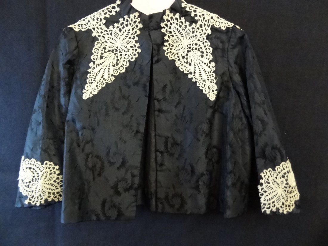 VINTAGE CHILD'S JACKET / BED COAT, HAND MADE, BLACK ON : VINTAGE CHILD'S JACKET / BED COAT, HAND MADE, BLACK ON BLACK DESIGN SATIN/SILK WITH LACE APPLIQUES ON FRONT, BACK AND ARMS. TWO HOOK AND EYE CLOSURES ON FRONT. 9'' ARM INSEAM, AT SHOULDER 12 1/2'' LON