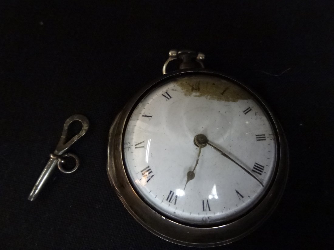 POCKET WATCH IN SILVER ENCASEMENT, CASE HAS MAKER'S MAR: POCKET WATCH IN SILVER ENCASEMENT, CASE HAS MAKER'S MARKINGS, THE OUTER ENCASEMENT BACK IS DENTED AND WATCH FACE HAS SOME STAINING, INCLUDES KEY.