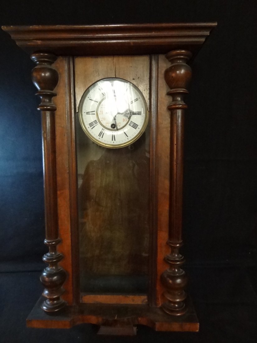 ''R = A'' WALL CLOCK, WOOD CASE 27'' TALL X 14'' WIDE X: ''R = A'' WALL CLOCK, WOOD CASE 27'' TALL X 14'' WIDE X 7'' DEEP, ENAMELED FACE WITH BRASS TRIM, BOTH ROMAN AND ENGLISH NUMERALS, PENDULUM MARKED ''R = A''. BEAUTIFUL AND WARM BROWN WOOD. CROWN WOOD P