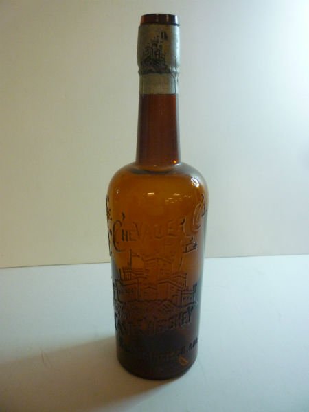 ANTIQUE BOTTLE: THE CHEVALIER CO, AMBER GLASS: ANTIQUE BOTTLE: THE CHEVALIER CO, AMBER GLASS WITH ORIGINAL LABEL AROUND THE NECK. ALSO HAS GLESS CORK TOP. BOTTOM MARKED "384"