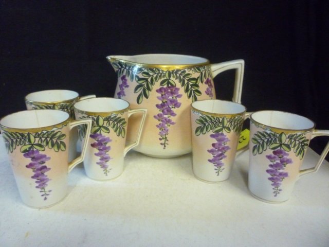 PITCHER AND CUPS: HAND PAINTED NIPPON, PITCHER 6" TALL: PITCHER 6" TALL AND 9" WIDE. AS FOUND. 3 WITH THIN CRACKS. GOLD TONED GILT TRIM. 6 PIECES