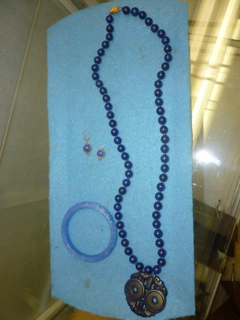 CARVED NECKLACE, BRACELET, AND EARRING SET: NECKLACE: NECKLACE DARK BLUE BEADING WITH LARGE CARVED PENDANT (APPROX. 2" ACROSS), BRACELET LIGHTER BLUE CARVED GLASS AND STERLING SILVER SET EARRINGS WITH BLUE STONE INSET (ONE MISSING ATTACHMENT)
