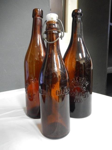 ANTIQUE BEER BOTTLES LOT INCLUDES 3 ANTIQUE AMBER BEER: LOT INCLUDES 3 ANTIQUE AMBER BEER BOTTLES. ONE IS APPROX 11.25" TALL AND MONOGRAMMED "TERRE HAUTE BREWING CO., TERRA HAUTE, IND., THIS BOTTLE NOT TO BE SOLD" TWO IS APPROX 11.5" TALL, SLIGHTLY CURVED 
