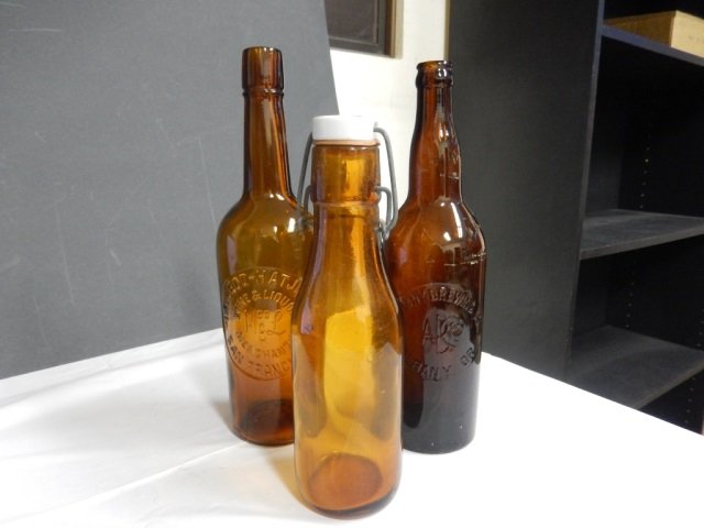 ANTIQUE BEER BOTTLES LOT INCLUDES 3 ANTIQUE AMBER BEER: LOT INCLUDES 3 ANTIQUE AMBER BEER BOTTLE. ONE IS APPROX 9.75" TALL W/O MARKING BUT DOES HAVE ORIGINAL PAINTED COW STOPPER. TWO IS APPROX 12" TALL AND MONOGRAMMED "MCLEOD-HATJE CO. WINE & LIQUOR MERCHA