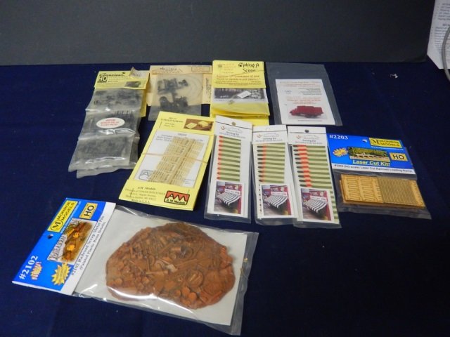 TRAIN MODELS PIECES: LOT INCLUDES. ALL UNOPENED: RAILWAY HERITAGE HO MILK CANS (30), 12-OAKKETS (SKIDS) AM MODELS, (3)FRENCHMAN RIVER AWNING KITS HO SCALE, MONROE MODELS #2102 RAILROAD SCRAP METAL PILE AND #2203 LASER CUT
