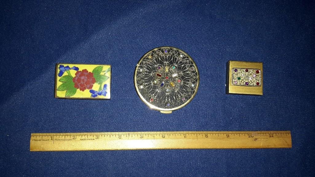 Decorative Vintage Compact and Boxes (3): Lovely bejeweled makeup compact with mirror 3 inches across. Cloisonne Floral metal match holder and small metal bejeweled pill box. All are in good condition and show some wear. 