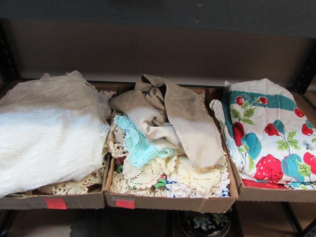 Various Linens: Large assortment of embroidered and crocheted tabled toppers, lace table toppers, suede table cloth, vintage strawberry design cotton table cloth and more.