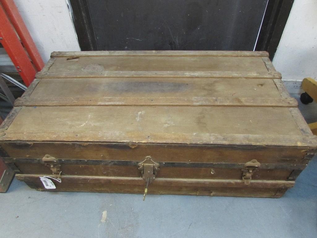 Trunk with Key: Trunks shows age. Key included. Two latches and metal handles on either side. Measures 39 1/2" long x 21 3/4" by 12 3/4". Wood, cloth and metal. 