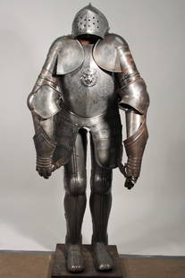 Reproduction Suit of Armor: helmet, brass plate, and legs are ornately etched, brass plate has lion head with jeweled eyes. All pieces show some rust. Stand not included.