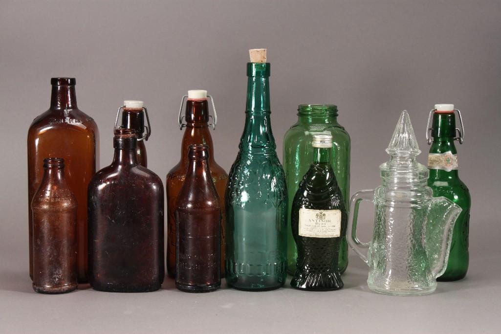 Vintage Glass Bottles (11): Green, Amber and Clear glass bottles. One 10 inch tall Amber Mineral Bottle, a 10 inch Amber Fischer bottle, a 12 inch green wine bottle and more.