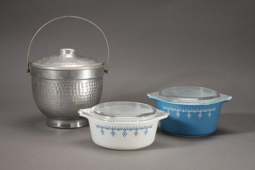 Lidded Pyrex Bowls and Ice Bucket(3): Blue and white pyrex lidded bowls, both are in good condition and have a 6'' diameter. Hammered aluminum ice bucket with lid and handle marked Nasco Italy, shows signs of age and wear, 6'' tall.