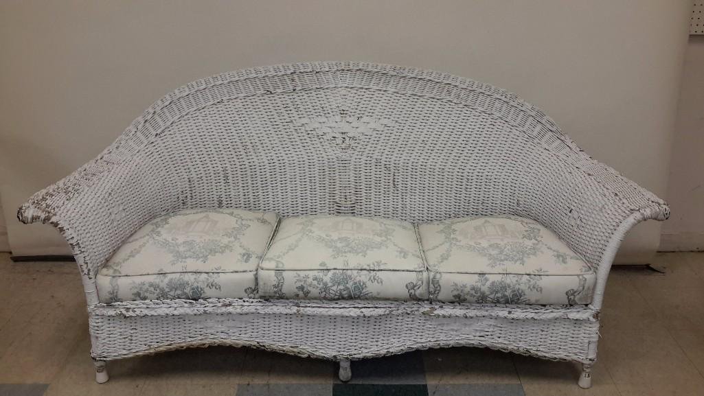 Vintage Wicker Sofa: White wicker sofa with curved back and arms, 36 in h x 24 in d. Wicker and cushions show wear from outdoor use.