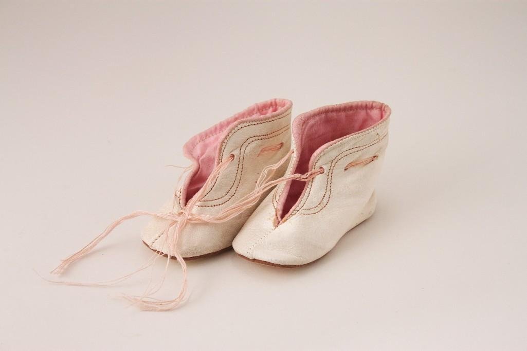 Leather Doll Shoes: Soft white kid leather with pink thread trim, pink satin lining, soft sole. Sole of shoe is 3.25" long. Very old, thread laces are worn. Very preciousdoll shoes.