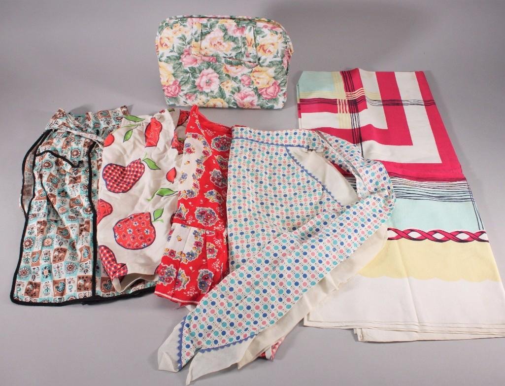 Vintage Aprons & Tablecloth (6): Four aprons, one cherry, one polka dot, and two floral design, tablecloth (has some stains), and more. Items are in good pre-owned condition.