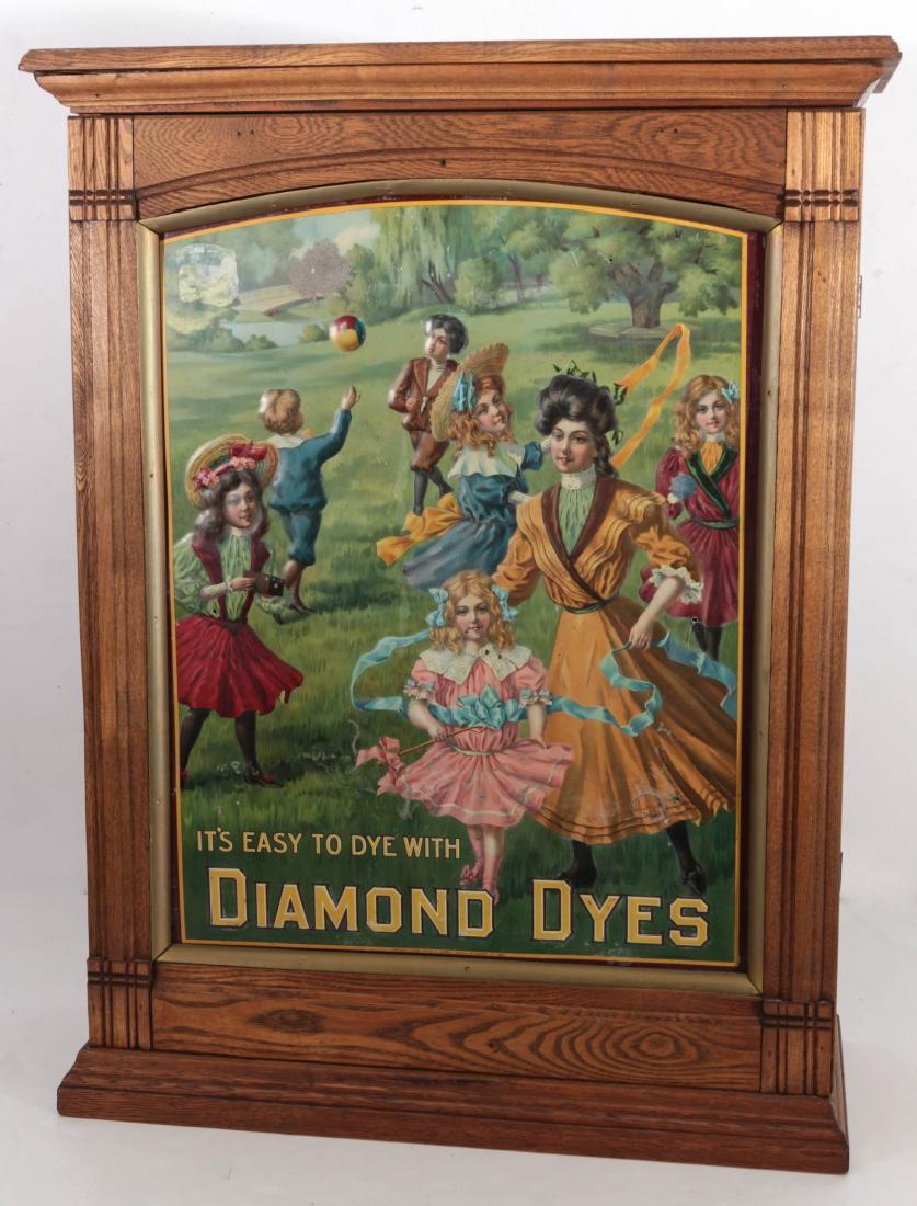 A CIRCA 1900 DIAMOND DYES 'GOVERNESS' CABNET: An ash wood cabinet with hinged front door set with a colorful tin lithograph advertising sign picturing a governess and children at play outdoors, the back merchant side with two sliding doors, the i