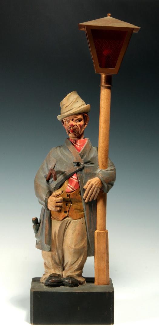 A KARL GRIESBAUM CARVED WOOD WHISTLER AUTOMATON: The standing figure and lamp post with clockwork mechanism, whistling feature produced by operating bellows and musical tubes, the head rotates side-to-side as the song evolves. The maker's mark on th