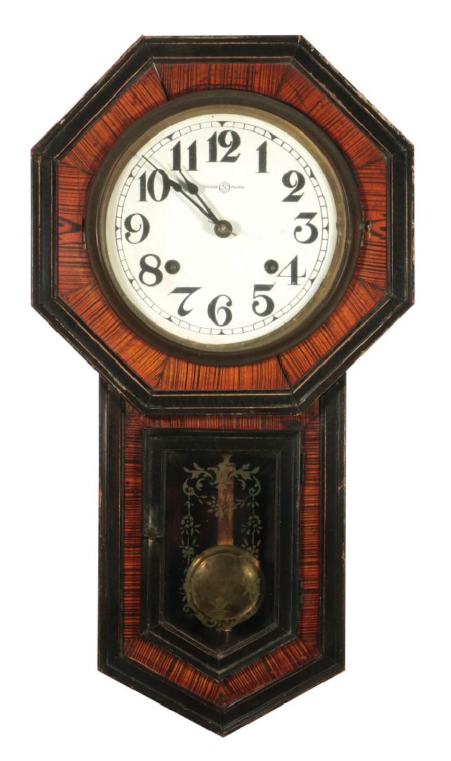 A SESSIONS LONG DROP OCTAGON SCHOOL HOUSE CLOCK: An octagon head schoolhouse clock with long drop and faux wood grain decoration within the ebonised molded trim, stenciled decoration on the door, replacement paper dial, 30 hour time and strike movem
