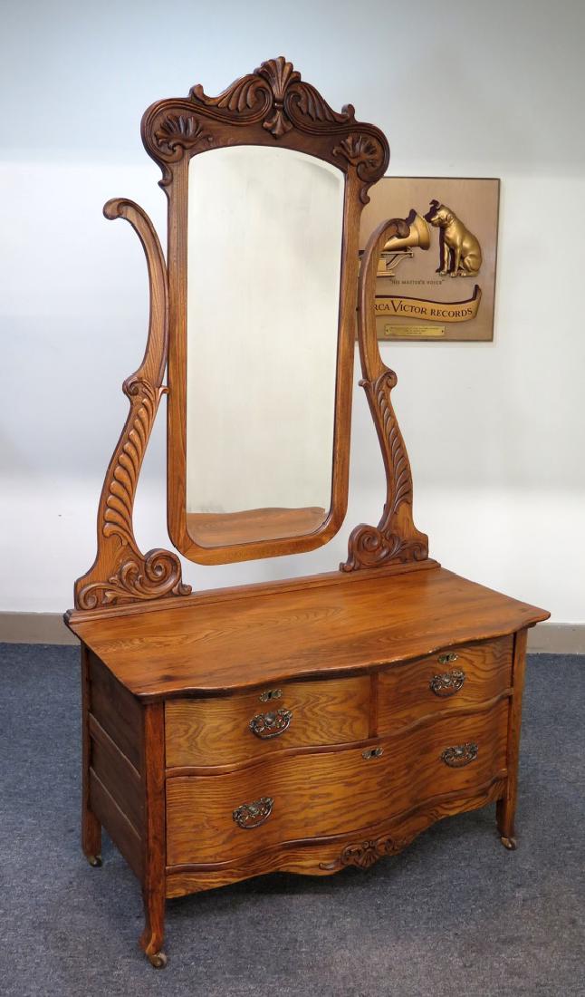 A CIRCA 1890 PRINCESS WISHBONE MIRROR DRESSER: Circa 1890s American ash wood dresser. Arched beveled mirror with applied carving supported by carved harps. Serpentine top over two large serpentine front drawers with original hardware. Measures 75