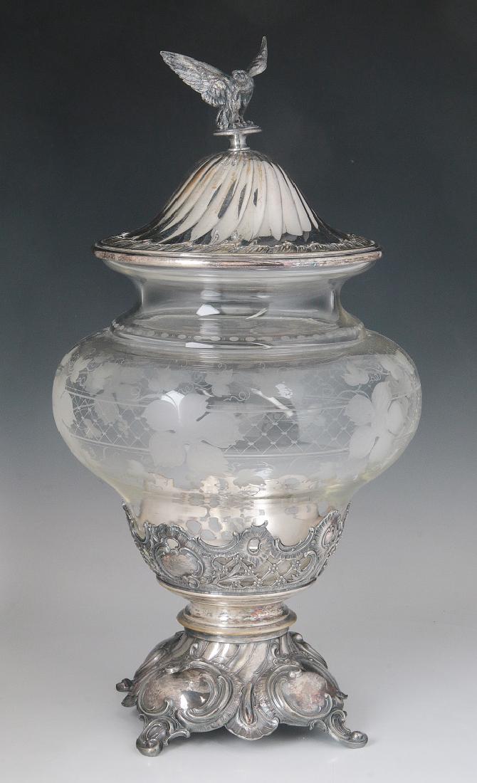 A CIRCA 1900 ETCHED CRYSTAL AND SILVER PLATE PUNCH: The double bellied crystal with etched motifs of flowers and foliate over a band of diaper patterning, the vessel set into a scalloped band of pierced silver featuring rocaille, cartouches and lattice