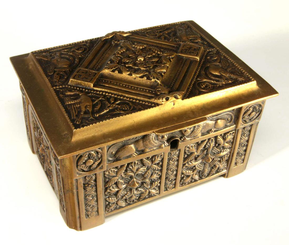 A MEDIEVAL REVIVAL STYLE BRONZE CASKET: A bronze casket cast with figures, symbols and designs of Medieval style, hinged lid opens to purple velvet interior, locking mechanism with key. Measures 3.5 x 4.5 x 6 inches.