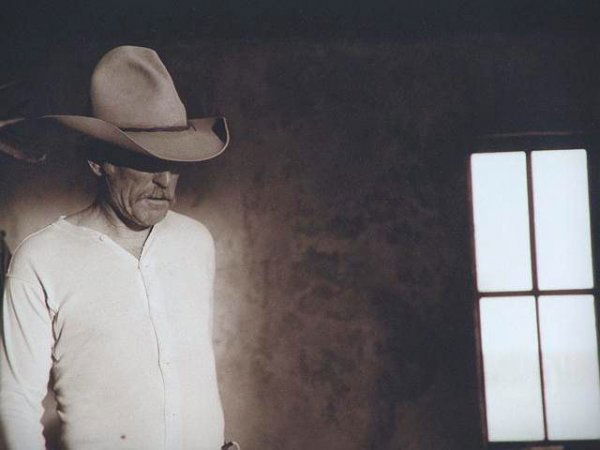 BILL WITTLIFF PHOTOGRAPH FROM LONESOME DOVE: An original silver gelatin print titled LONESOME DOVE: AUGUSTUS (ROBERT DUVALL & PANED WINDOW) pencil signed lower right, negative date of 1988, print date circa 1996. Actual image size 9 x 13.25 inch