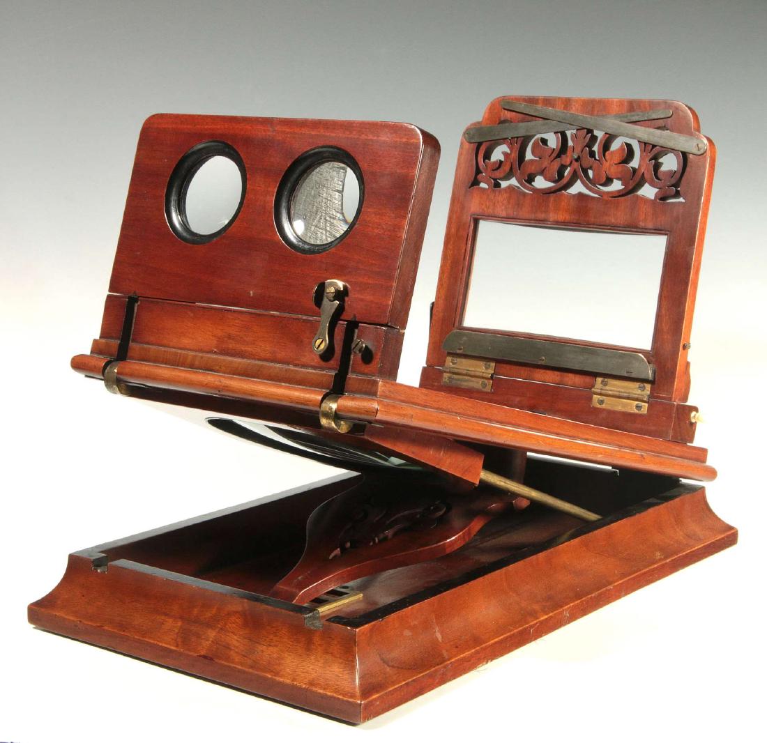 A GOOD TABLE-TOP STEREO GRAPHOSCOPE DATED 1887: A mahogany folding table-top viewer, with magnifying lens on bone-tipped upright rods. Hinged from beneath to allow for fold-away storage when using the stereo lenses. Entire apparatus folds down into