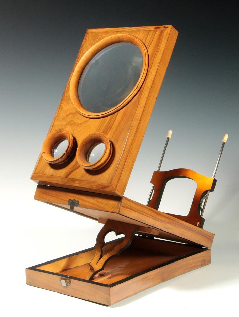 A GOOD 19TH C. BIEDERMEIER STEREO GRAPHOSCOPE: Honey-colored wood veneers, graphoscope and stereoscopic lenses in top panel,card holder mounted on bone-tipped rods, scroll cut support, folds flat. Measures 3.75 x 10.75 x 7 inches closed. We happil