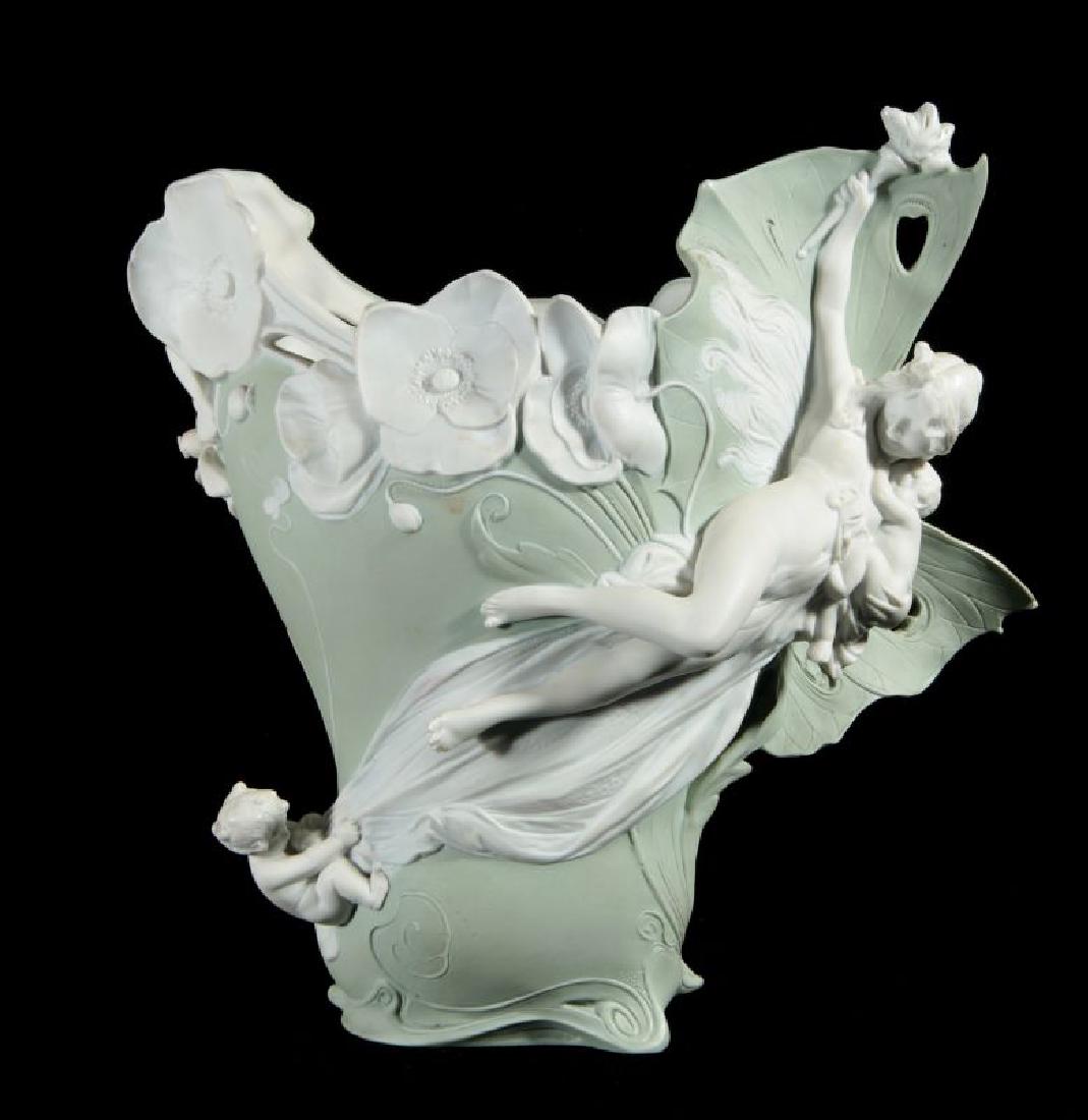 AN ART NOUVEAU JASPER VASE WITH MAIDEN: An airborne semi-nude maiden with infant floating across an asymmetrical vessel on butterfly wings. A chip on one wing, marked Germany, circa 1900. Measures 9.5 x 9 x 5 inches. We happily provide seam
