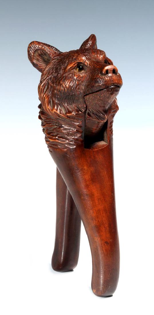 A BLACK FOREST CARVED WOOD FIGURAL BEAR NUTCRACKER: With inlaid glass eyes. Measures 7.5 inches. We happily provide seamless in-house packing and shipping services on nearly everything we sell.