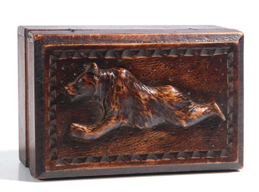 A CIRCA 1900 BLACK FOREST PUZZLE BOX WITH BEAR: The hinged lid with bas relief bear, chip carved border and stippled ground, mystery puzzle locking feature: the bear can be slid forward to lock the lid in place, or slid back to unlock the hinged li