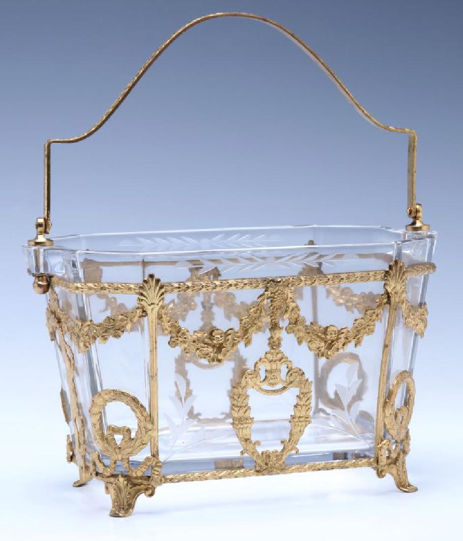 A RARE HEISEY OCTAGON ICE BUCKET WITH ORMOLU: The cut crystal rectangular crystal with canted corners mounted with a bail handle and encased in a footed ormolu frame with laurel rails and garland festoons, each end centering a standing female in 