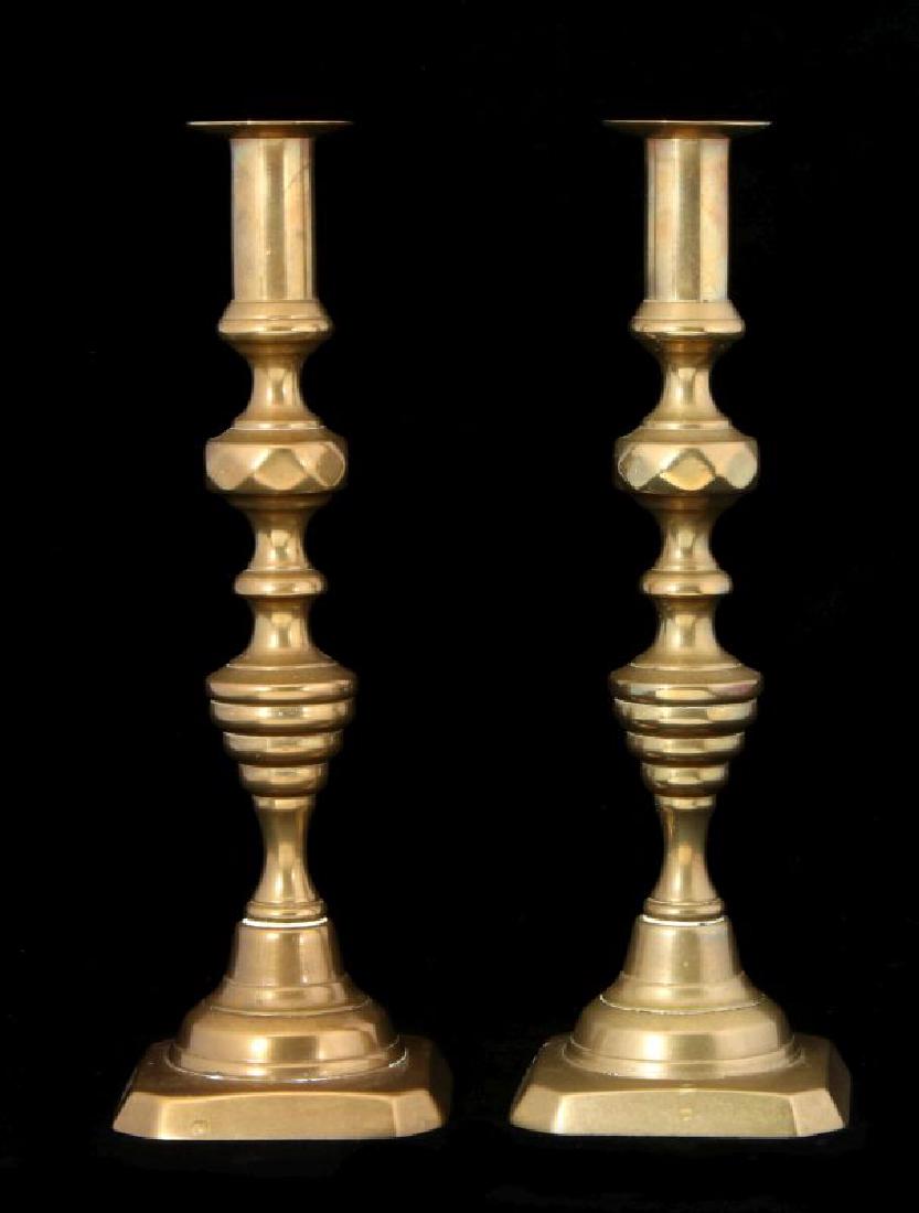 A PAIR 19TH C. BEEHIVE PATTERN CANDLE STICKS: Each with a circular ring lozenge knob above a turned and tapering reeded stem, surmounted by a cylindrical nozzle and circular dish form bobeche, raised on a square base with chamfered ends, 'push-up