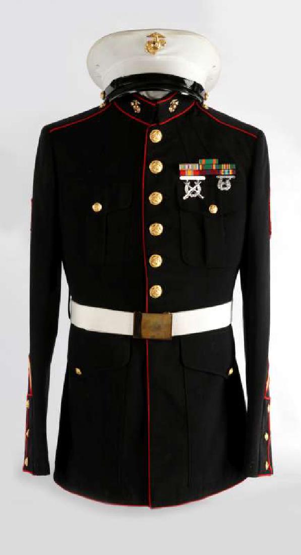 A USMC SERGEANT DRESS BLUES DISPLAY: 1980s era uniform with Sgt chevrons, gilt buttons, seven place ribbon bar, Rifle and Pistol expert badges, white belt and visor cap. Includes a tan shirt and tie underneath. Mounted on a bust form man