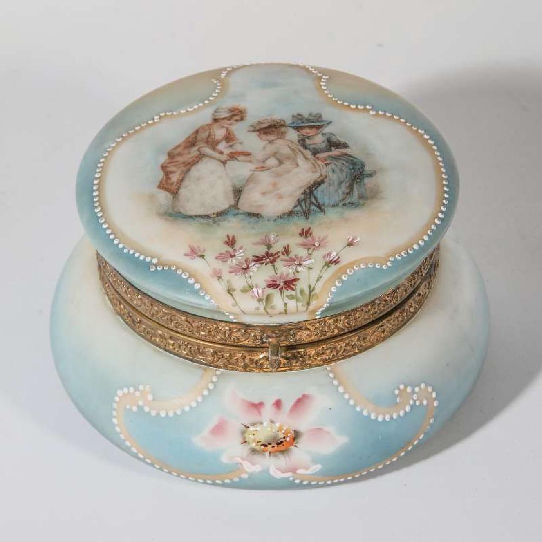 A LARGE MONROE GLASS NAKARA BOX WITH BERRY LADIES: A blue ground decorated opaque glass box with decorated reserve of florals and ladies in Victorian dress sitting down with berries, white enamel beaded framing, ormolu rims, signed on the base. Measur