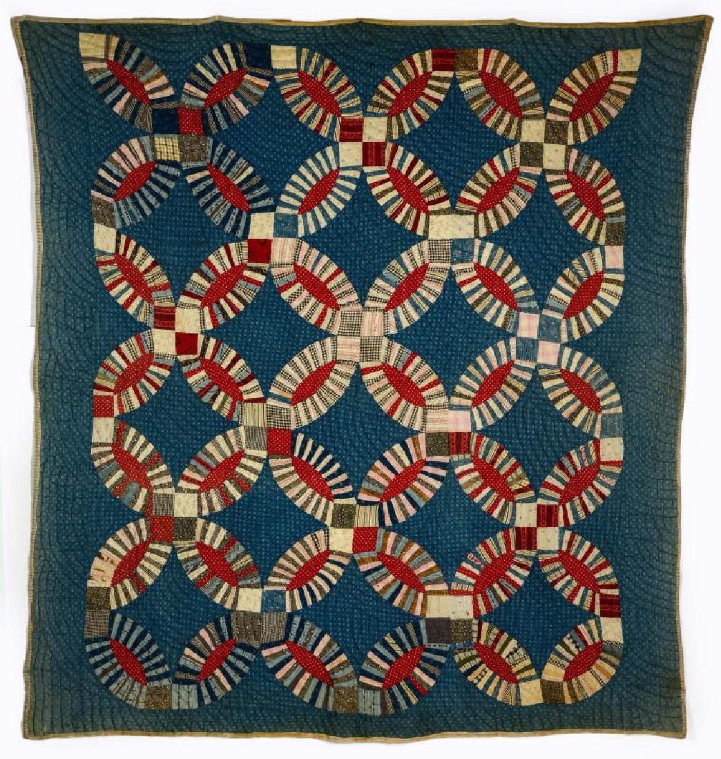A VINTAGE 'DOUBLE WEDDING RING' QUILT: Polychrome fabrics on a sprigged blue ground, blue sashing, striped ticking binding and backing, high loft, hand quilted. Measures 74 inches x 69 inches. We happily provide seamless in-house packing a