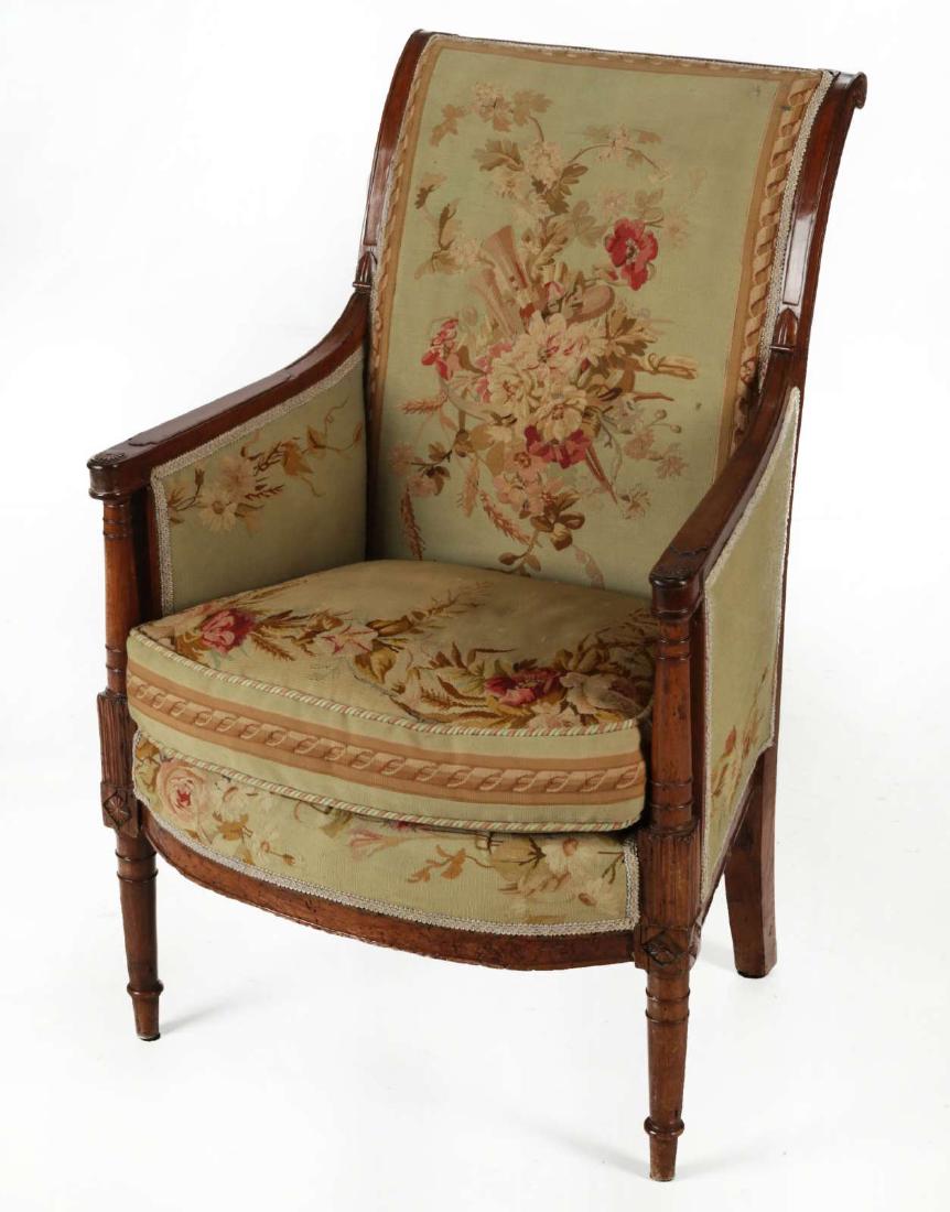 A 19TH CENTURY LOUIS XVI STYLE TAPESTRY BERGERE: The scrolled crest rail above a rectangular padded back and sides with rounded patera armrests braced by upright supports ending in carved stiff leaves over carved patera blocks enclosing a conforming