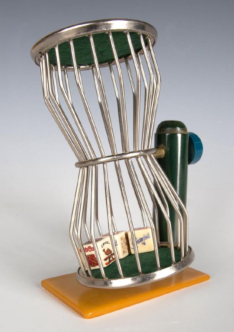 A 1930s CHUCK-A-LUCK DICE GAME WITH CATLIN PLASTIC: a trade stimulator with flat rectangular caramel catlin base with green column and blue knob supports the 'birdcage' with dice that advertise Old Gold, Camel, Chesterfield and other cigarette brands.