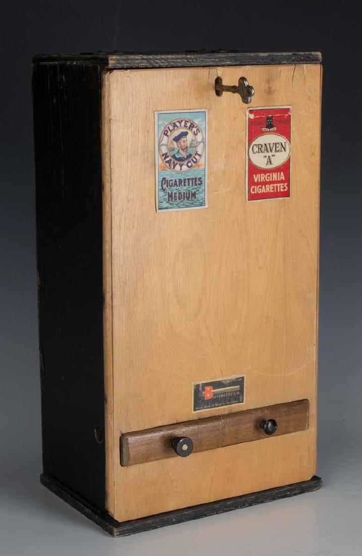A BRITISH MID 20TH CENTURY CIGARETTE DISPENSER: The wood cabinet with upper coin slots. Measures 14 x 7 1/2 x 6 We happily provide seamless in-house packing and shipping services on nearly everything we sell.
