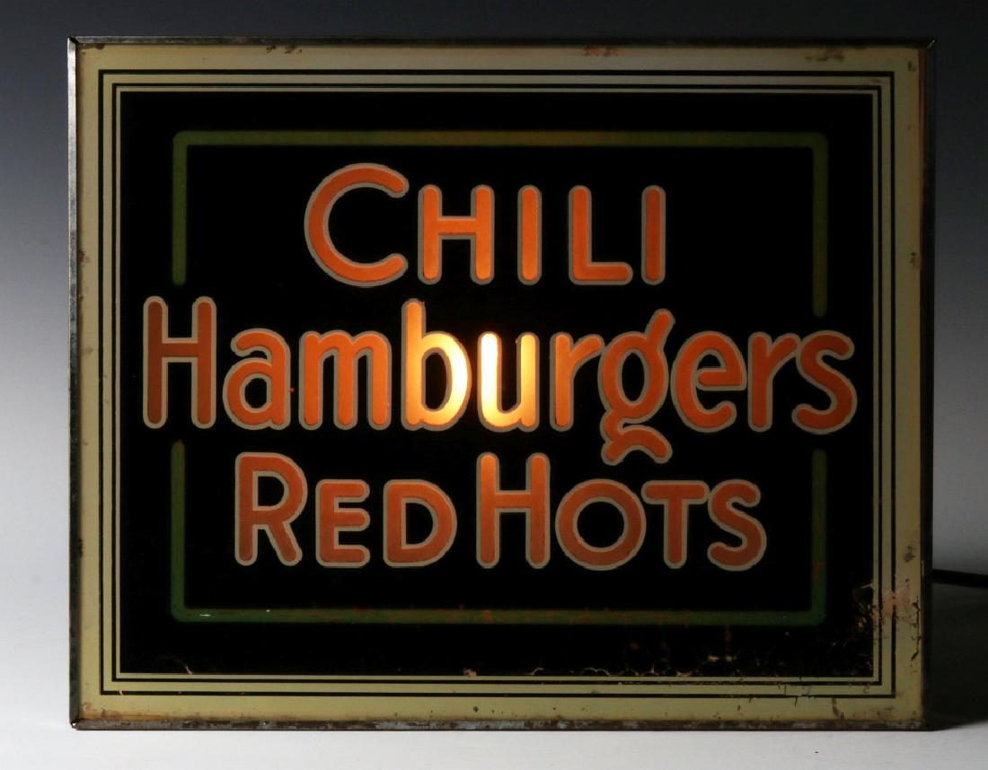 A 1930S BACKLIT REVERSE PAINTED DINER SIGN: A glass front sign announcing CHILI HAMBURGERS RED HOTS Measures 12 x 15.25 x 9.5 inches. We happily provide seamless in-house packing and shipping services on nearly everything we sell.