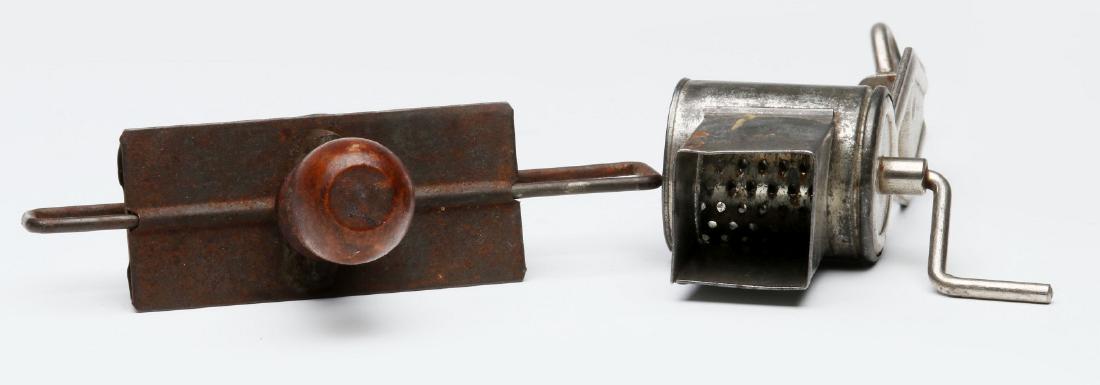 TWO ANTIQUE NUTMEG GRATERS: Tin examples, one with wooden knobs, unmarked. Measures 5.5 x 5 inches and 6.75 x 1.5 inches. We happily provide seamless in-house packing and shipping services on nearly everything we sell.