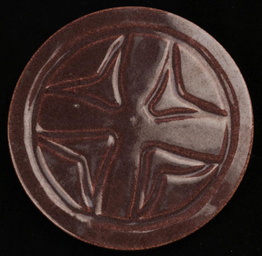 A CIRCULAR ART POTTERY TILE SIGNED CLEVELAND 1923: With carved geometric designs, scratched markings back side. Measures 5.25 inches. We happily provide seamless in-house packing and shipping services on nearly everything we sell.