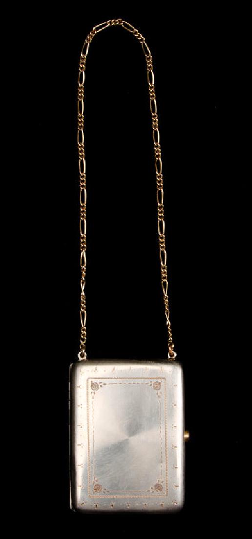 A VINTAGE MINAUDIERE COMPACT: Hand chased with a jeweled catch, long chain handle, lid contains a beveled mirror, the base holds two hinged wells, unmarked. Measures 3.5 x 2.5 inches with a drop of 7.5 inches. We happily provide s
