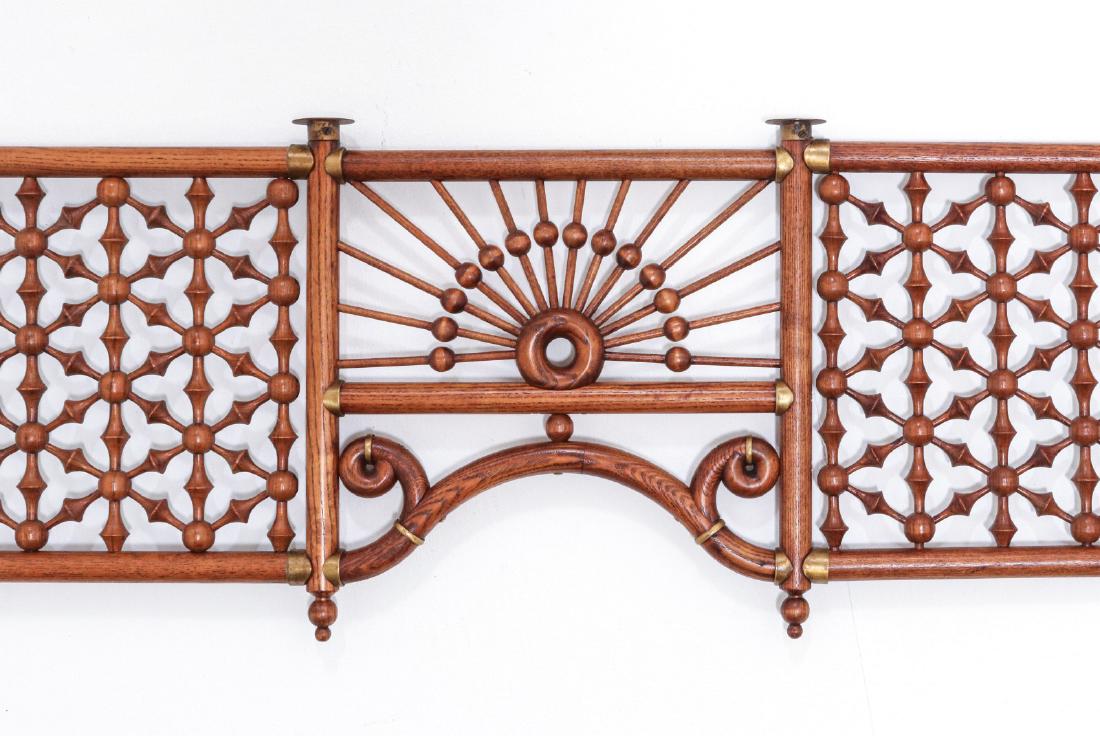 A CIRCA 1890 OAK A STICK-AND-BALL FRETWORK TRANSOM: An intricate gridwork of oak finial-and-ball design within oak dowel work frame, and centered by bent oak scroll work below a stick-and-ball sunburst, brass fittings. Measures 14.5 x 58 x 1 inches. We