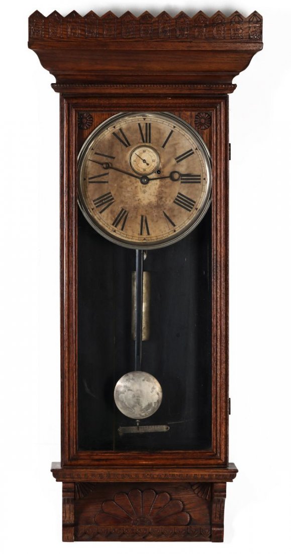 A WM. L. GILBERT CO. REGULATOR WALL CLOCK NO. 14: A 19th century wall clock with pressed oak case, Roman numeral paper dial, eight day, signed on the dial and again with a paper label inside the case, time only. Measures 47 x 20.75 x 8 inches. We hap