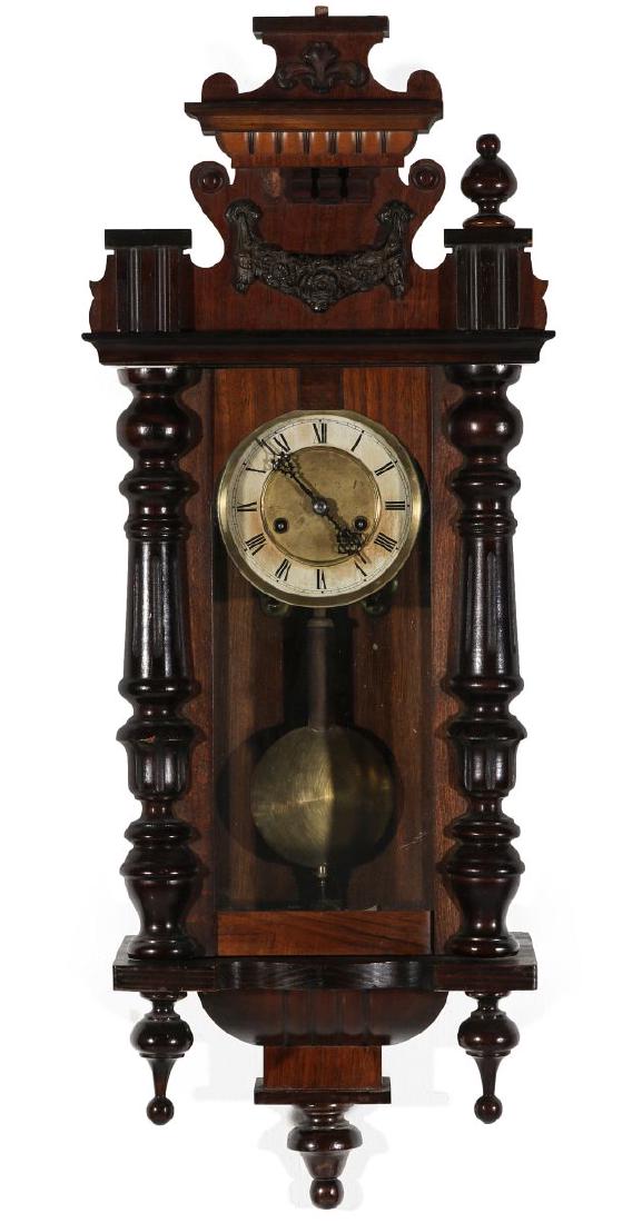 AN ORNATE HAMBURG AMERICAN WALL REGULATOR: A late 19th/early 20th century wall hanging clock with elaborate two-toned case covered with applied carvings, half-columns, and trim decoration, turned wood finials and half-columns, brass dial with